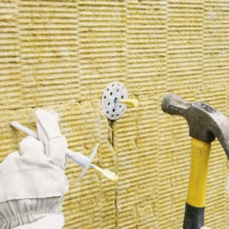 Isolera utvändigt: Isolerfästena knackas in i hålen Isolera utvändigt: Isolerfästena knackas in i hålen